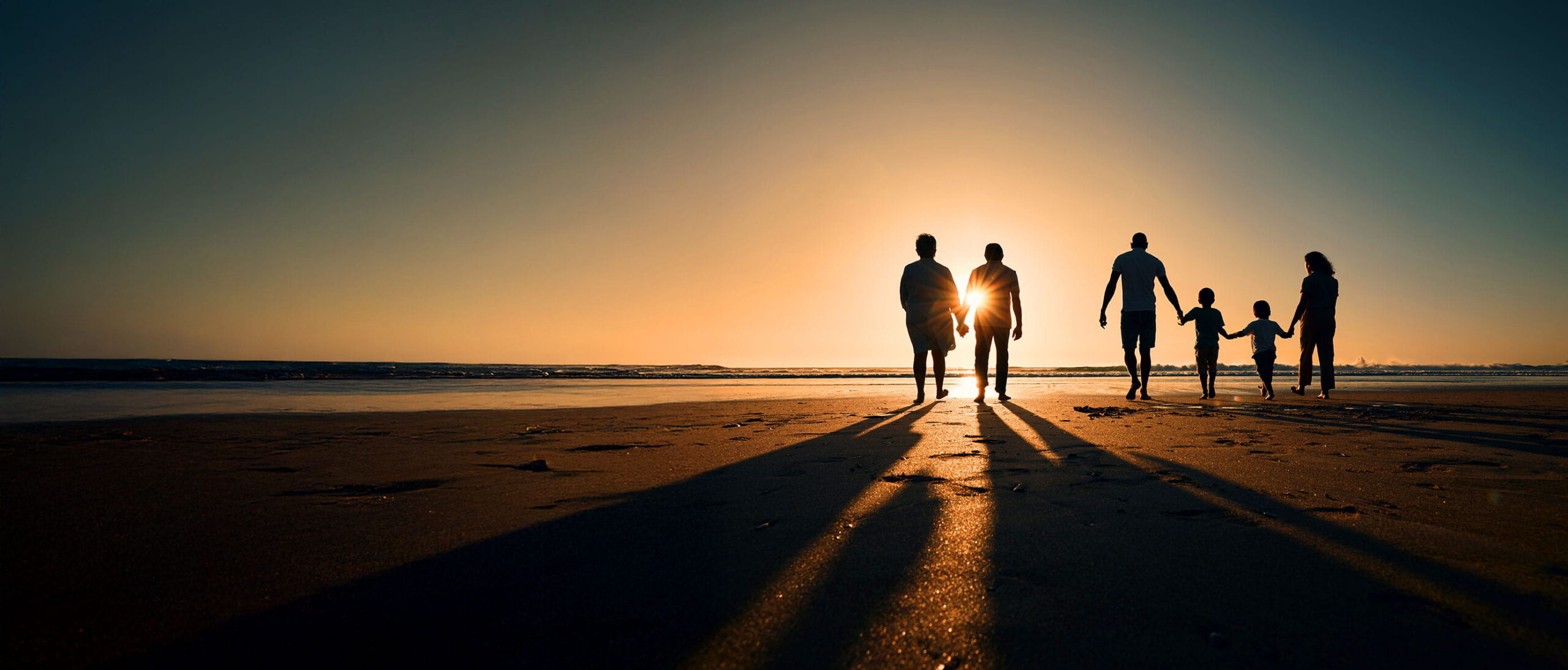 Family of five silhouetted walking along a beach at sunset